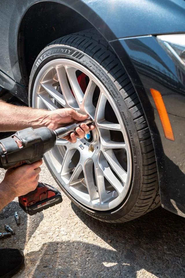 Tyre fitter fastening a wheel with an impact wrench